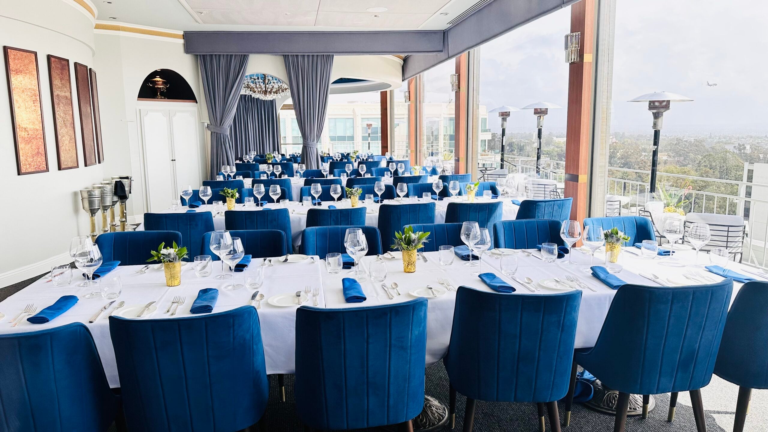 The Downtown Room at Mister A's set for a large private event with blue velvet chairs and city views