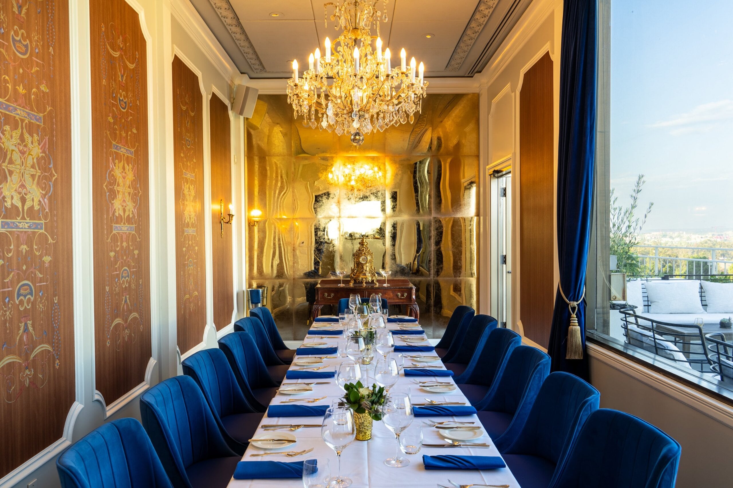 The Blue Room at Mister A's with gold marquetry panels, crystal chandelier and a long table set for a private dinner